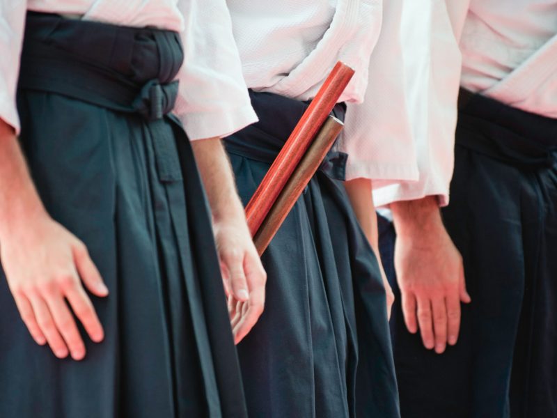 Alligned Aikido fighters. Selective focus set on wooden staff.